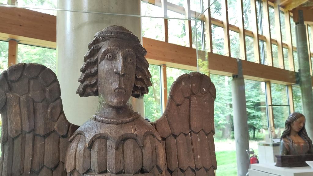 Carved wooden angel scuplture in a glass and wood framed museum gallery